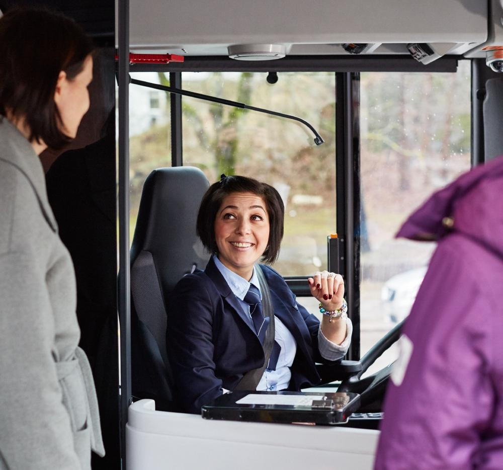 Bussförare hälsar resenärer välkomna.
