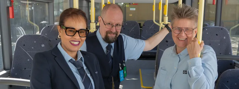 Tre bussförare pratar med varandra framför röd buss.